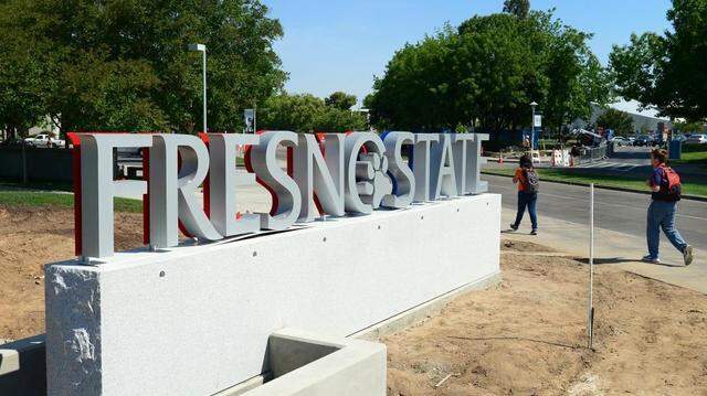 Students walk by a new gateway sign at the entrance to Fresno State at Maple and Shaw avenues. The stone and metal sign lies across from a sculptural element, called a sprout to reflect the school's agriculture, nature, native history, programs and education, made of perforated metal and wood.